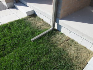 Downspout discharging right beside a foundation instead of six feet away, a common cause of basement moisture found during a moisture and mould home inspection in Kingston Ontario by Equinox Home Inspections