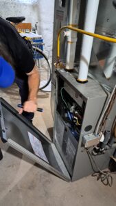 Rick Conley of Equinox Home Inspections inspecting a furnace during a home inspection in Kingston and area.