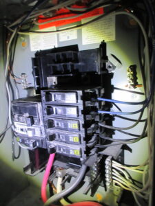 Electrical panel showing missing breakers, open slots and questionable grounding during a Kingston home inspection